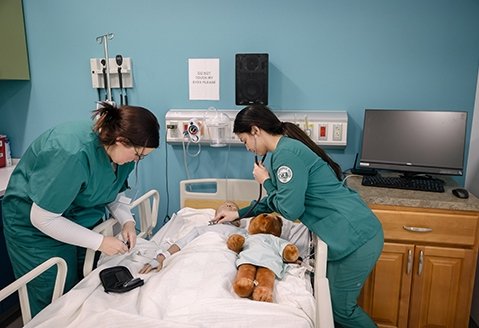 Two Nursing students work in a simulation lab